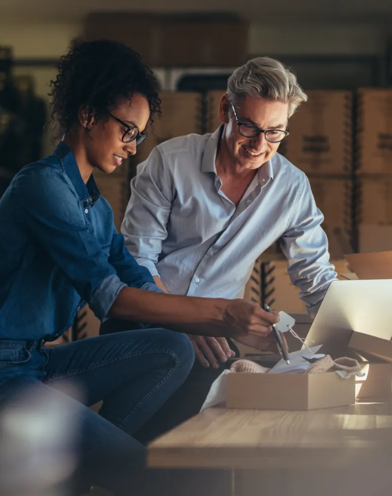 Two colleagues packing orders at a warehouse workstation