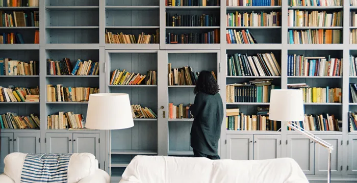 A person looking at a book shelf.