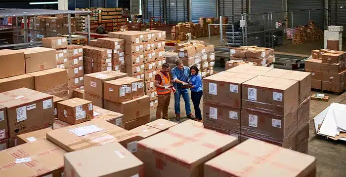 Employees working in a warehouse surrounded by packages.