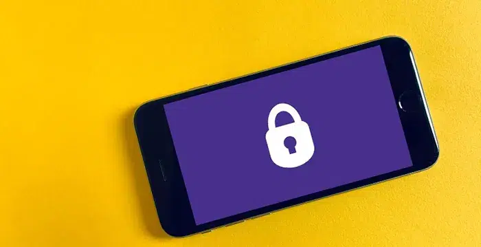 Black cell phone on a yellow background.