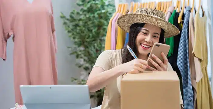 A women with a hat holding a phone.