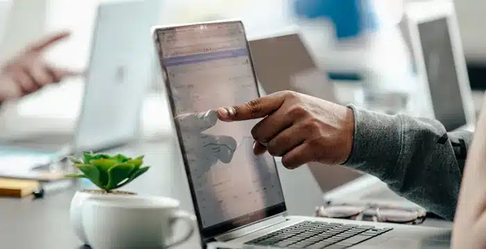 An image of a person pointing to a graph on a laptop.