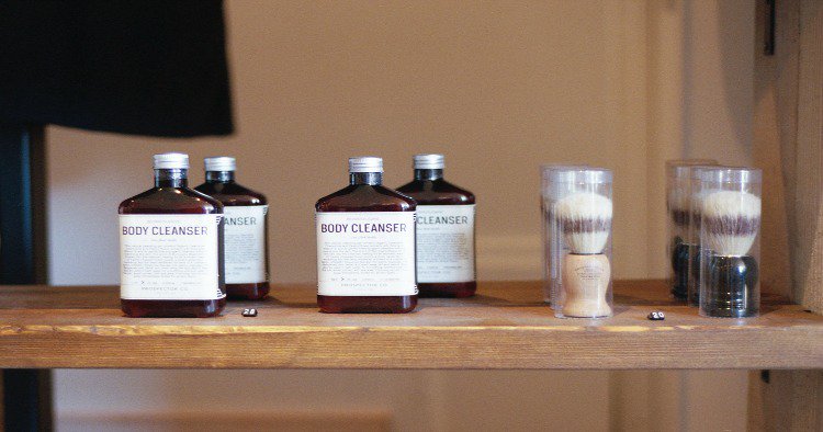 glass bottles labeled body cleanser and round brushes