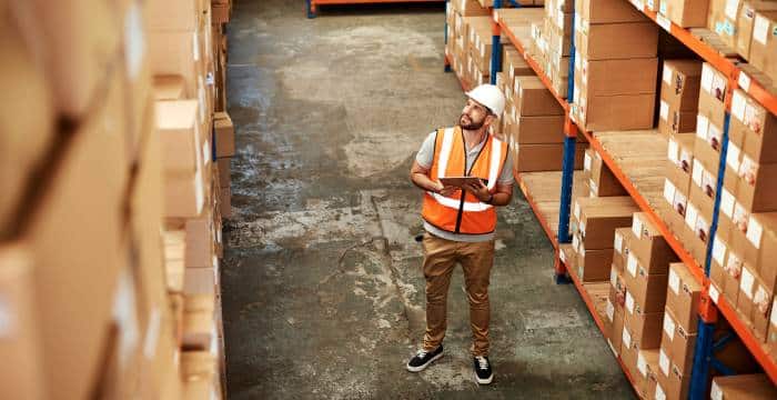 Worker using inventory control system to check stock in warehouse