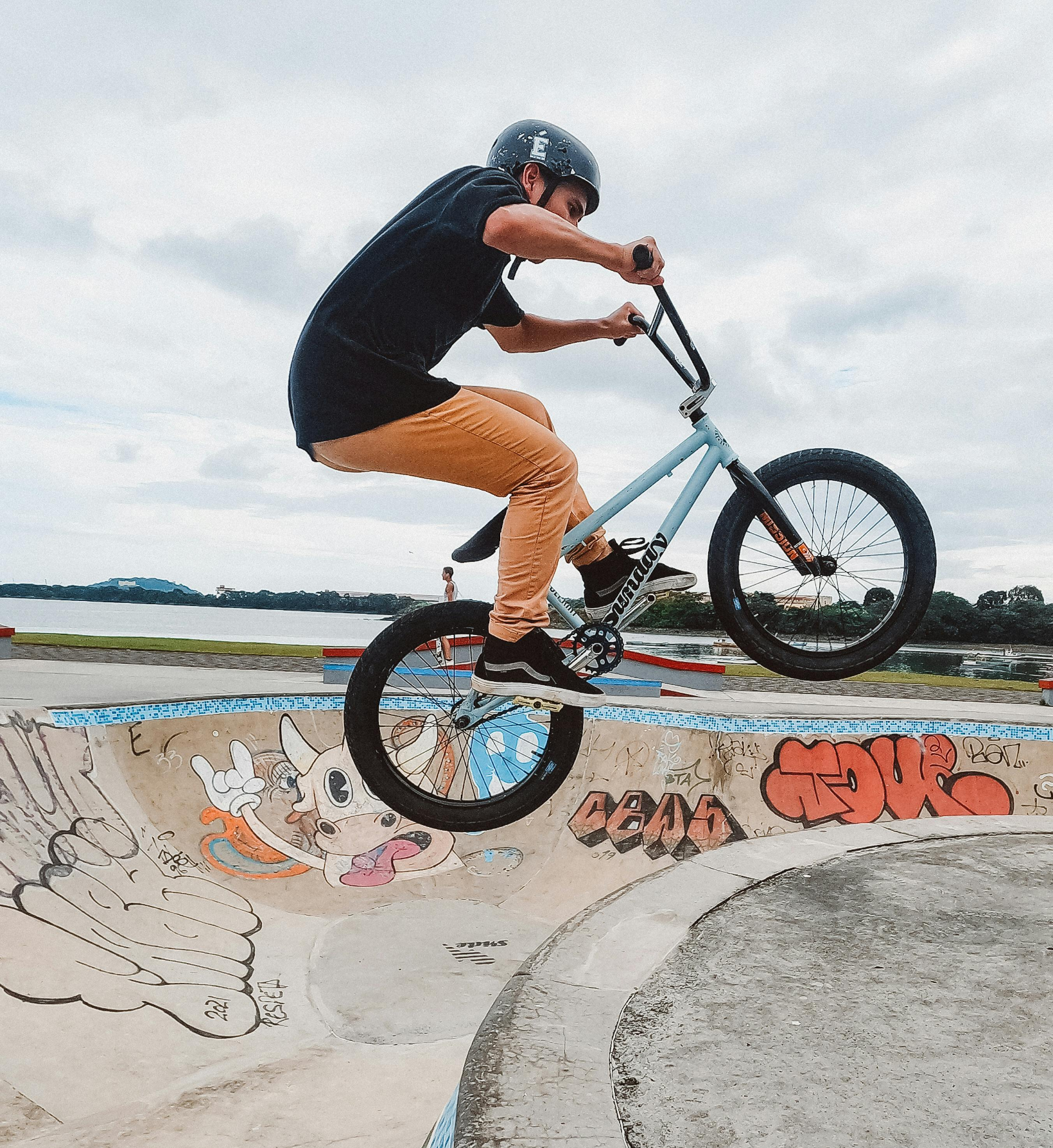 Person performing a BMX trick in a graffiti-decorated skatepark bowl.